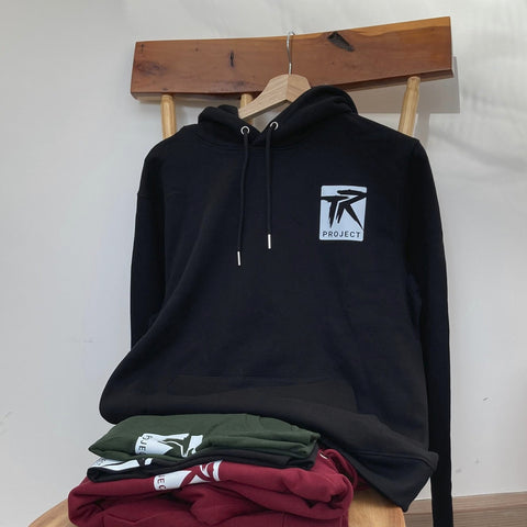 Black hoodie with a logo on a wooden stool against a white wall