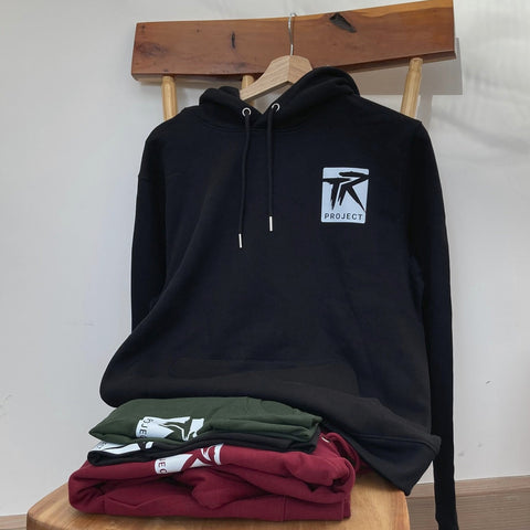 Black hoodie with a logo on a wooden stool against a white wall