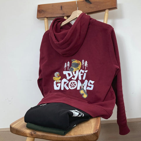 Burgundy hoodie with "Dyfi Groms" logo
on a wooden stool against a white wall