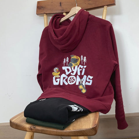 Burgundy hoodie with "Dyfi Groms" logo on a wooden stool against a white wall